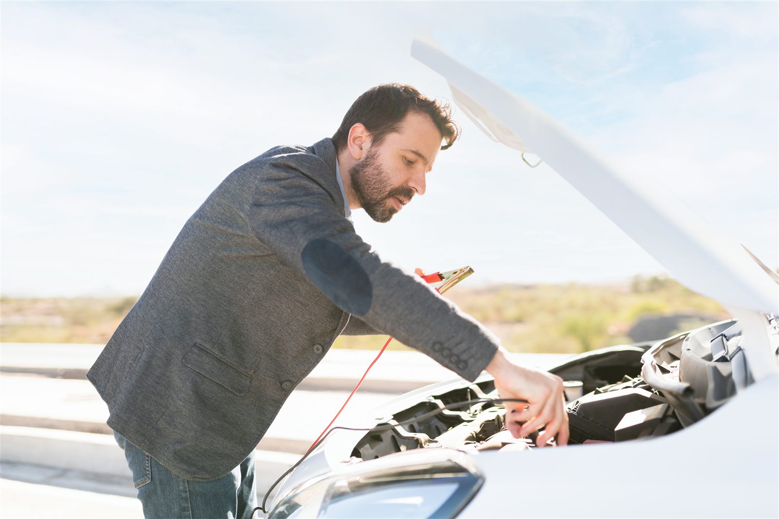 Jumper cables clamped onto a car battery under an open hood